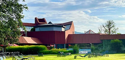 Das Foto zeigt das Rotherma von außen. Vor dem Gebäude sieht man Wiese und Liegen. 