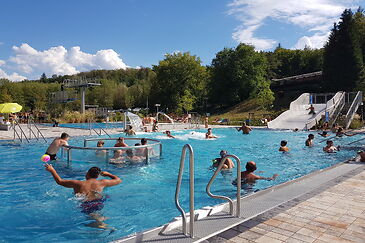 Das Foto zeigt das große Schwimmbecken mit Wasserrutsche und Badegästen.